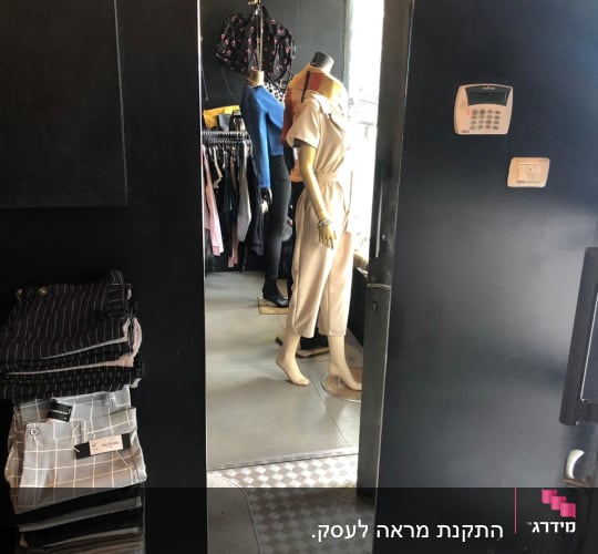 בובת תצוגה משתקפת במראה זכוכית בחנות בגדים